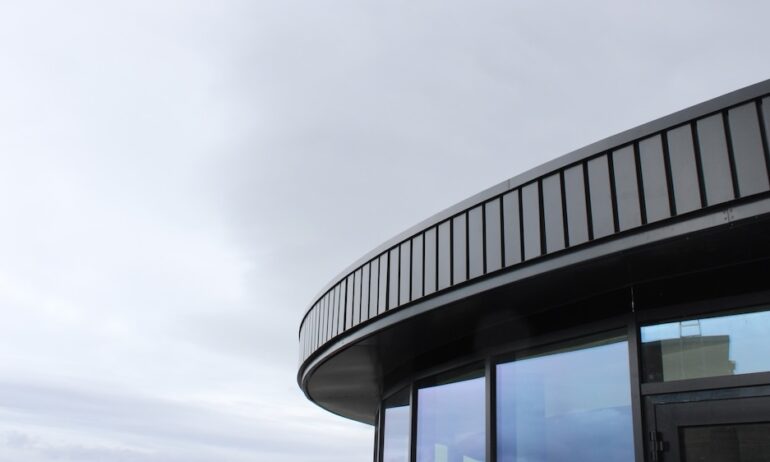 Modern architectural design featuring a rounded building edge with sleek metal cladding and large windows, reflecting Alutech Precision Engineering's focus on innovative aluminum solutions in metal fabrication.